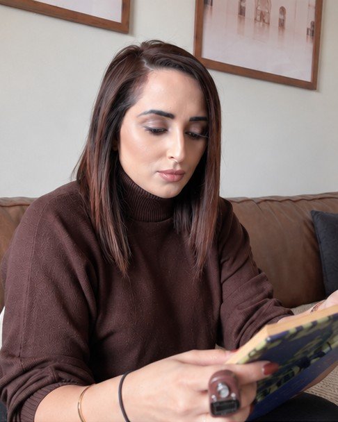 Farkhana reading on a leather sofa